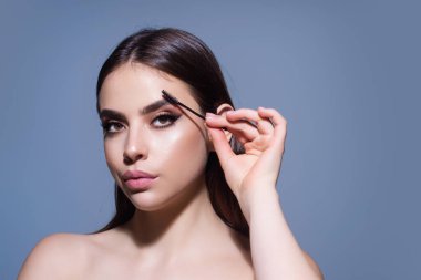 Woman comb eyebrows with eyebrow brush. Care for brows, eyebrows lamination. Brow beauty procedures. Beautiful woman with long eyelashes, eyebrows