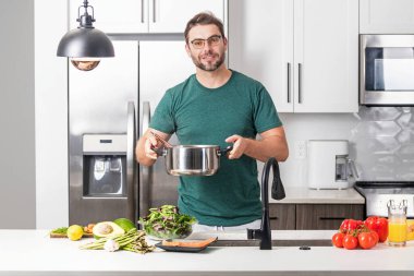 Aşçı mutfakta yemek pişiriyor. Şef aşçı tencereli bir yemek hazırlıyor. Menü tarifi sağlıklı yemek. Şef modern mutfakta yemek pişiriyor. Olgun aşçı mutfakta yemek hazırlıyor.