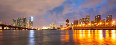 Miami şehrinin gökdelenleri ve deniz üzerindeki köprüleri yansıtıyor..