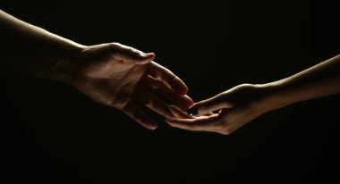 İki el uzanıyor. İzole edilmiş siyah arka planda kurtuluşa uzanan bir el uzatmak. Kadın ve erkeğin el ele tutuşması gibi. Erkek ve kadın el ele tutuşuyor