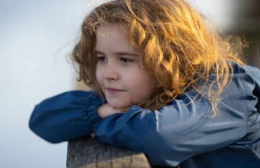 Hayalperest küçük. Rahatlamış çocuk parkta esintiyi hissediyor. Çocuk yüzünde düşünceli bir ifade. Geleceğin düşünürü sakin bir günün tadını çıkarıyor. Huzurlu bir çocuğun portresi. Hayal gücünü keşfeden sevimli çocuk.
