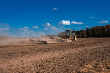 Traktör tarlada toprak sürüyor. Mavi gökyüzüyle tarlada toprak. Kırsal tarım arazilerinde traktör. Tarım traktörü toprakta çalışıyor. Çekici tarla sürme çiftliği. Çiftlik arazisi