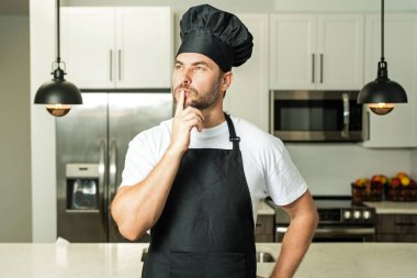 Üniformalı yakışıklı aşçı mutfakta yemek yapıyor. Restoran menüsü konsepti. Fırıncı üniformalı İspanyol adam. Aşçılık ve aşçılık. İş üniformalı, siyah önlüklü, şef şapkalı bir aşçı.