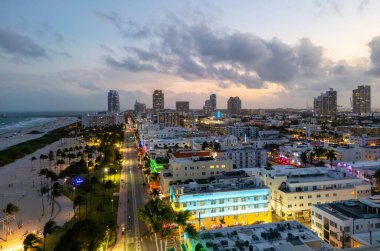 Miami Sahili Günbatımı hava manzarası. Alacakaranlıkta Miami 'nin göbeğinde. Güney Sahili neon ışıkları. Tropik Miami kıyısı manzarası. Ocean Drive Art Deco binaları. Miami kıyı şeridinin havadan görüntüsü