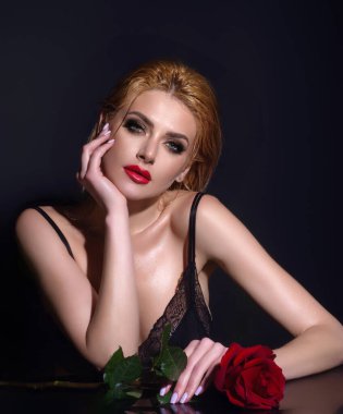 Çekici, sevimli, rüya gibi bir kızın portresi. Elinde kırmızı güller, siyah stüdyo arka planında izole edilmiş.