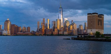 New York şehri. New York şehir manzarası. New York 'taki Lower Manhattan ve One World Trade Center. Manhattan 'ın gökdelenleri New York körfezinin dalgalanan sularının yanında mavi gökyüzüne karşı. New York gökdelenleri