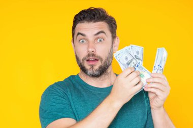 Adam sarı stüdyonun arka planına para koydu. Dolar banknotları olan zengin adamın portresi. Dolar banknotları olan başarılı bir adam. Zengin milyoner.