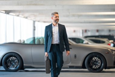 Bankacı kariyeri. Zengin iş adamı başarının tadını çıkarıyor. Şık takım elbiseli lüks iş adamı. Pahalı arabanın önündeki zengin adam. Lüks iş seyahati. Klasik takım elbiseli, kendinden emin zengin bir iş adamı.