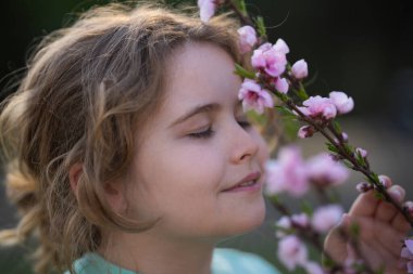 Bahar çocuk portresi. Çiçek açan bir çayırdaki çocuk. Doğadaki çocukluk sevinci. Bahar günü çiçekli bir çocuk. Gülümseyen çocuk bahar doğasında açık havada oynuyor. Rüya gibi bahar