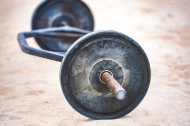 Halter ekipmanı. Spor geçmişi. Yaz sporu için kumda halter. Kum arka planda halter. Spor salonunda halterle idman yapıyorum. Spor afişi