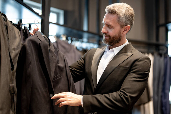 Бутик-консультант помогает клиенту найти идеальный костюм. Коллекция роскошных костюмов премиум-класса. Элегантный костюм идеально подходит для бизнесмена. Хорошо подогнанный костюм