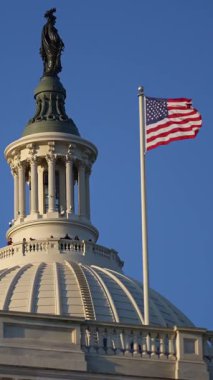 Washington DC 'deki Kongre Binası yakınlarında Amerikan bayrağı sallanıyor. ABD sembolü. Kongre Binasında Birleşik Devletler bayrağı. Capitol 'de gökyüzüne karşı bayrak. Dalgalı Amerikan bayrağı. Özgürlüğe oy verin. Capitol Tepesi Bayrakları