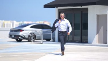Tişörtlü başarılı bir iş adamı açık havada koşuyor. İşadamı ofis işlerine dışarıda koşar. Olgun bir iş adamı sokakta koşar. Hızlı ve hızlı bir iş. İş adamı hareket halinde. İş portresi. Yavaş çekim