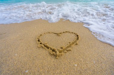 Okyanus dalgaları arka planı. Tropik okyanus dalgaları. Mavi deniz manzaralı. Kalp kumda çizilmiş. Dalgalar kalp şeklinde bir işaret oluşturuyor. Kumsalda aşk. Romantik yaz. Kumdan yapılmış bir kalp. Aşk ve okyanus dalgaları