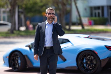 Lüks bir arabanın yanında zengin bir işadamı. Zengin bir iş adamı. Zarif zengin iş adamı. Pahalı arabası olan bir avukat. Premium arabada duran zengin bir işadamı. İş başarısı. Zenginlik kavramı