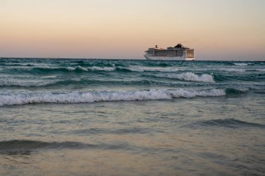 Okyanusta bir gemi turu. Günbatımında lüks bir yolcu gemisi. Yolcu gemisi olan Miami Plajı. Turkuaz su ve yolcu gemisi. Kıyıya yakın bir turist gemisi. Okyanus dalgaları ve gemi teknesi