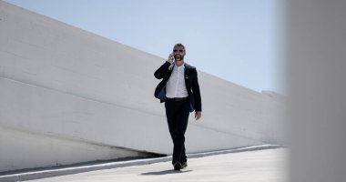 İş adamı dışarıda telefonla konuşuyor. Telefon görüşmesinde başarılı bir adam. İş adamı dışarıyı arıyor. Cep telefonu olan yakışıklı bir iş adamı. Cep telefonundan konuşan kendine güvenen bir adam. Çevrim içi iş