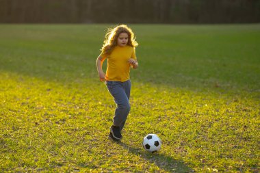 Mutlu çocuk futbol oynuyor. Çocuk çimlerde futbol topunu tekmeliyor. Futbol topuyla koşan bir çocuk. Futboldan zevk alan oyuncu çocuklar. Çocuklar futbol maçı. Futbol oynayan çocuk.
