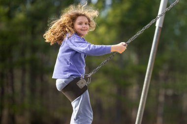 Heyecanlı çocuk eğleniyor. Çocuk bahçesinde mutlu bir çocuk. Havada sallanan tasasız çocuk. Mutlu çocuklar dışarıda oynuyor. Genç çocuk heyecanla sallanıyor. Dışarıdaki oyuncu çocuk. Komik çocuk yüzü.