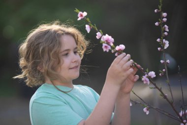 Bahar çocuk portresi. Çiçekli bir çayırdaki sarışın çocuk. Doğadaki çocukluk sevinci. Bahar günü çiçekli bir çocuk. Gülümseyen çocuk bahar doğasında açık havada oynuyor. Rüya gibi bahar çocuğu yüzü