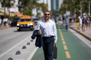 İş adamı işe yürüyerek gider. Hispanik iş adamı sokakta güven içinde yürüyor. Ofis çalışanı ofise gidiyor. Olgun bir iş adamı şehirde yürüyor. Dışarıda dolaşan gömlekli bir iş adamı.