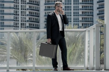 Dışarıdaki telefondan iş adamı aradı. Kendine güvenen bir adam arama yapıyor. Takım elbiseli bir yönetici arıyor. Ciddi bir iş adamı stratejiyi tartışıyor. İş adamı cep telefonundan arıyor. İş çağrıları