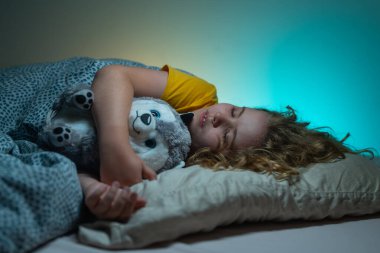 Çocuklar için yastık ve battaniye. Küçük çocuk uyuyor. Sevimli çocuk yatakta uyuyor. Uyuyan çocuk. Çocuk karanlık odada uyuyor. Evdeki bir yatakta uyuyan çocuk