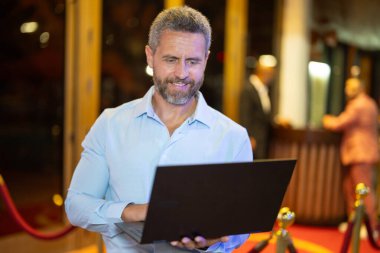 Gece lambasında dizüstü bilgisayar kullanan bir iş adamı. İşadamı sokakta dizüstü bilgisayarda çalışıyor. Gece kulübü yakınlarında orta yaşlı bir iş adamı iş planlıyor. İş 40 'larda. Serbest Çalışan açık havada dizüstü bilgisayarda geziniyor