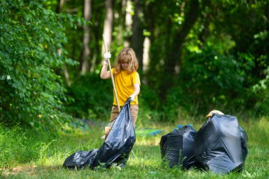 Küresel çevre kirliliği. Çocuk dışarıda plastik çöp topluyor. Çevre koruma kavramı. Çocuk çöp torbasına atık koyuyor. Eko çocuklar gönüllü. Çevre kirliliği