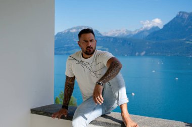 Kaslı bir adam dağ Alpleri manzarasında rahatlar. Alp Gölü 'nde yakışıklı bir turist. Yazın poz veren güçlü, seksi bir adam. Hayalperest, kaygısız bir gezgin. Açık havada insan özgürlüğü