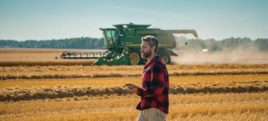 Buğday tarlasında çiftçinin portresi. Çiftçi çiftlikteki hasatı inceliyor. Altın buğday çiftçiliğe hazır. Çiftçilerin ektiği topraklar. Çiftçi bitkilerin büyümesini inceliyor. Tarlada yürüyen bir tarım işçisi