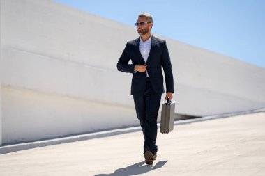 Açık hava iş portresi. Dışarıda yürüyen bir iş adamı. Şirket lideri harekete geçti. Çantalı takım elbiseli adam. İşadamı işe gidiyor. Çantası olan bir iş adamı. İşadamı ofise git.
