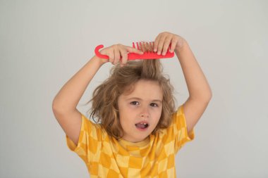 Saç kremi ve çocuk saçı için şampuan. Kıvırcık saçlı çocuk saç fırçası ya da tarak tutuyor. Sağlıklı saçlar. Çocuk kontrolsüz saçlarını tarıyor.