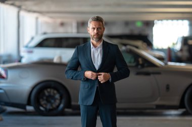 Zengin bir iş adamı pahalı lüks bir arabada. Takım elbiseli zengin bir iş adamı. Şehirdeki başarılı zengin iş adamı. Kendine güvenen bir iş adamı. Başarı işi. İş adamı sokakta yürüyor