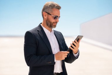 Açık havada tablet kullanan bir iş adamı. Tabletle başarılı bir yönetici. Şirket lideri tablet üzerinde çalışıyor. Zarif iş adamı tableti kontrol ediyor. Dijital aygıt kullanan işadamı