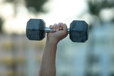 Dambıllar kol kola. Yetişkin bir adamın dambılları dışarı kaldırması. Kol kasları dambıl egzersizi yapıyor. Kol halteri tutun. Dambılı bir erkek kolunun yakın çekimi.