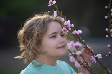 Bahar çocuğu portresi. Çiçekli bir çayırdaki sarışın çocuk. Doğadaki çocukluk sevinci. Bahar günü çiçekli bir çocuk. Baharda açık havada oynayan gülümseyen bir çocuk. Hayalci bahar çocuklarının yüzü