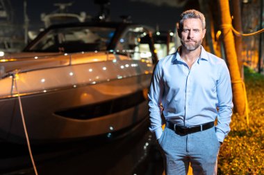 Yatın yanındaki zengin milyarder. Lüks yaşam tarzı olan zengin karizmatik milyarder iş adamı. Özel yatta milyarder bir adam. Finansal özgürlük. Milyarder bir iş adamıyla pahalı bir yat.