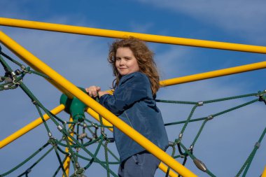 Çocuk dışarı tırmanıyor. Oyun parkına tırmanan aktif bir çocuk. Çocuk parka tırmanıyor. Mutlu çocuk dışarıda oynamaktan hoşlanıyor. Sevimli çocuk oyun alanında eğleniyor. Çocuk parka tırmanıyor