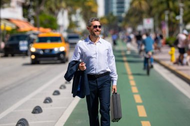 İş adamı işe yürüyerek gider. Hispanik iş adamı sokakta güven içinde yürüyor. Ofis çalışanı ofise gidiyor. Olgun bir iş adamı şehirde yürüyor. Dışarıda yürüyen bir iş adamı. İş biçimi