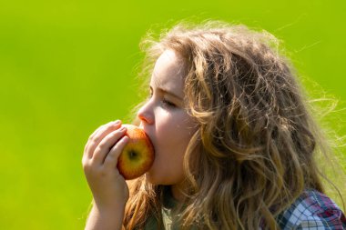 Çocuk bir elma yiyor. Çocuklar için olgun meyve. Çocuk elmayı ısırıyor. Çocuk sağlıklı yiyeceklerin tadını çıkarıyor. Bir çocuk kırmızı bir elma tutuyor. Yaz güneşi. Sarışın çocuk elmadan bir ısırık alıyor. Çocuklar için taze elma sağlıklı atıştırmalıklar.