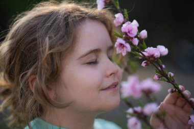 Bahar çocuğu portresi. Çiçekli bir çayırdaki sarışın çocuk. Doğadaki çocukluk sevinci. Bahar günü çiçekli bir çocuk. Baharda açık havada oynayan gülümseyen bir çocuk. Hayalci bahar çocuklarının yüzü