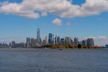 New York şehri. New York şehir manzarası. New York 'taki Lower Manhattan ve One World Trade Center. Manhattan 'ın gökdelenleri New York körfezinin dalgalanan sularının yanında mavi gökyüzüne karşı. New York gökdelenleri
