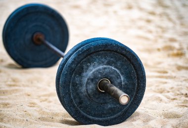 Halter spor ekipmanları. Spor geçmişi. Yaz sporu için kumda halter. Kum arka planda halter. Spor salonunun dışında halterle antrenman. Spor afişi