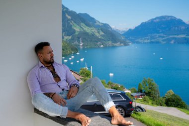 Kaslı bir adam dağ Alpleri manzarasında rahatlar. Alp Gölü 'nde yakışıklı bir turist. Yazın poz veren güçlü, seksi bir adam. Hayalperest, kaygısız bir gezgin. Açık havada insan özgürlüğü