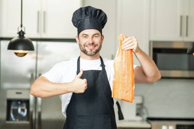 Modern mutfakta sağlıklı balık somonu hazırlayan bir adam. Yakışıklı adam evdeki mutfakta taze balık somonu pişiriyor.