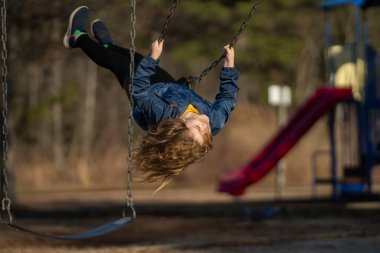 Çocuk salıncakta sallanıyor. Çocuk çocuk çocuk parkında sallanıyor. Parkta sallanan çocuk. Mutlu çocuk dışarıda oynamaktan hoşlanıyor. Sevimli çocuk oyun alanında eğleniyor. Çocuk parkında sallanıyor