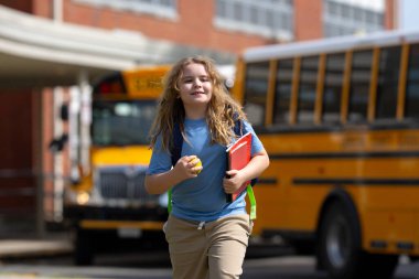 Okula dönelim. Genç öğrenciler için okul başlıyor. Okul otobüsünün yanında sırt çantalı bir çocuk. Çocuk okula gidiyor. Çocuk derse gidiyor. Okul çocuğu.