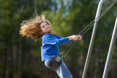 Çocuk salıncakta eğleniyor. Çocuk bahçesinde mutlu bir çocuk. Havada sallanan kaygısız çocuk. Mutlu çocuklar dışarıda oynuyor. Sarışın çocuk heyecandan titriyor. Dışarıdaki oyuncu çocuk. Komik çocuk suratı