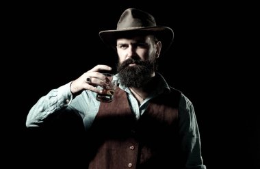 Sakallı adamın tuttuğu viski bardağı. Barda yalnız başına viski içen adam. Klasik bardakta viski. Viski tadı retro tarzında. Pahalı viski. Konyak ya da viski. Alkolik içecek.